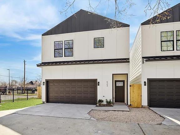 Two of the six Bianco Lane homes from the street, white siding with black standing seam accents over two-car garages, Bianco Lane, Houston TX 77091