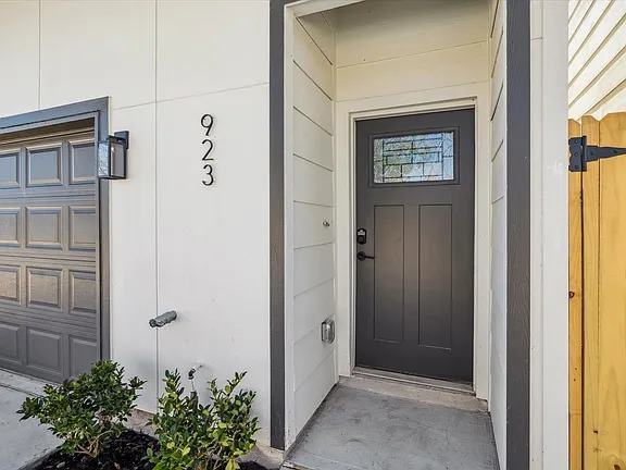 Covered entry at 923 Bianco Lane with a black three panel front door and a glazed transom light, Bianco Lane, Houston TX 77091
