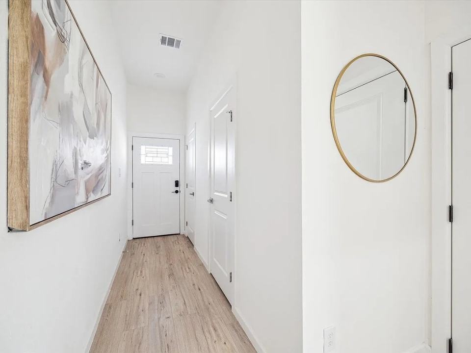 Hallway with a round mirror and light oak flooring, Bianco Lane, Houston TX 77091