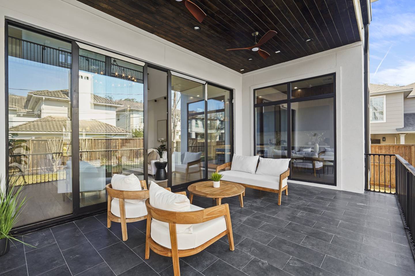 Covered patio with large black-framed aluminum sliding glass doors opening into the home