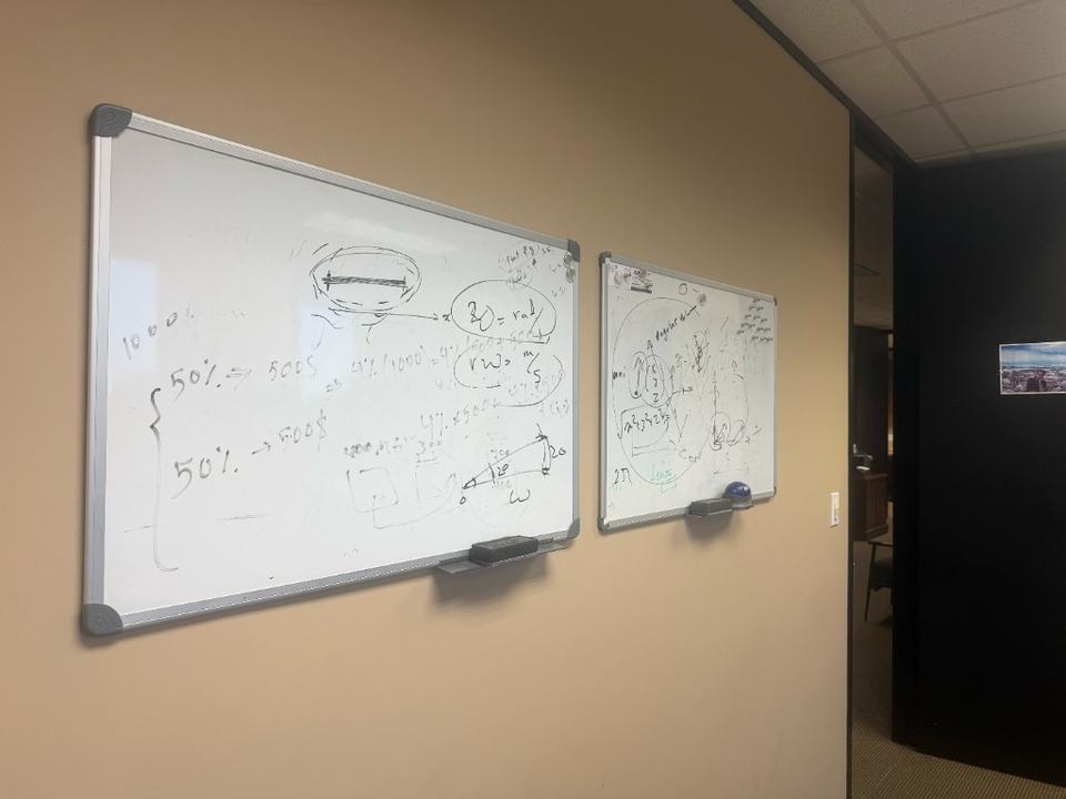 Two office whiteboards filled with Dr. Medai's mathematical models, diagrams, vectors, and working calculations